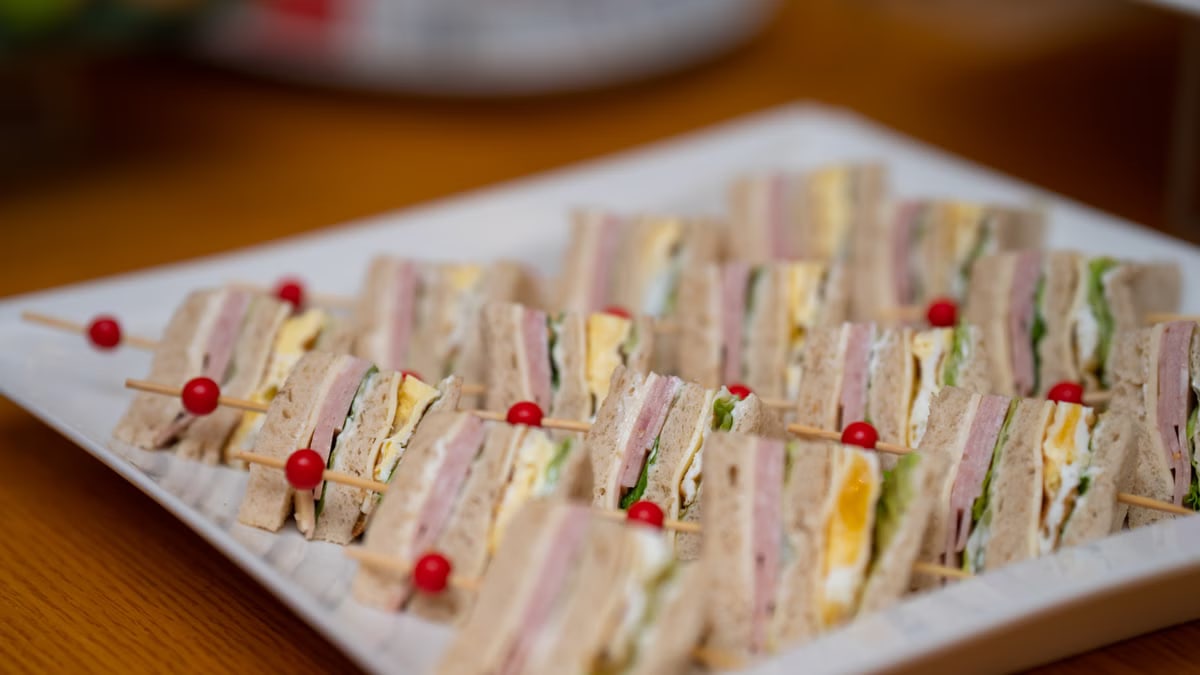 Delicious gourmet sandwich skewers with assorted meats, cheese, and fresh vegetables on a plate.